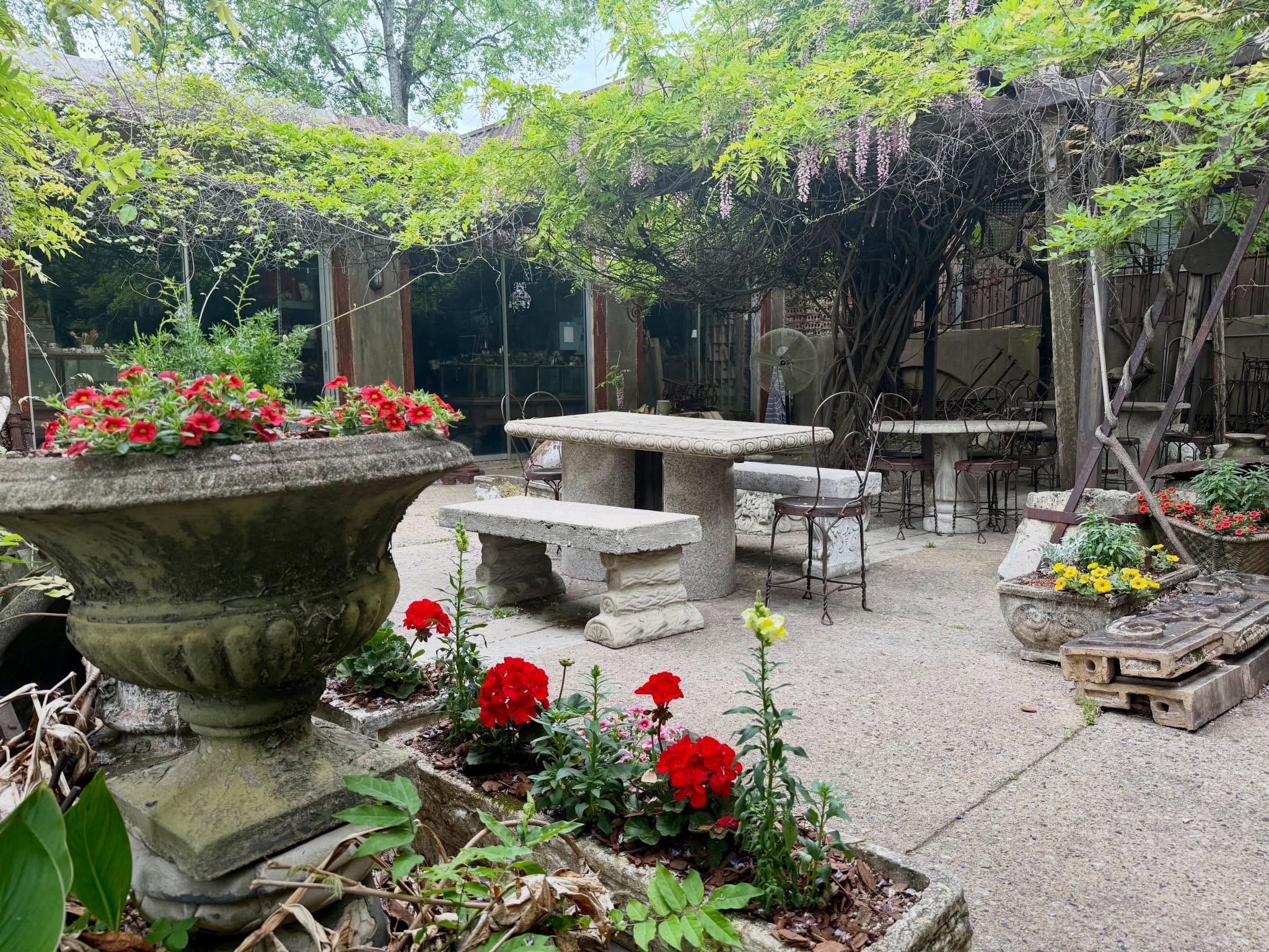 Stone dining table and benches under the wisteria arbor in The Garage courtyard