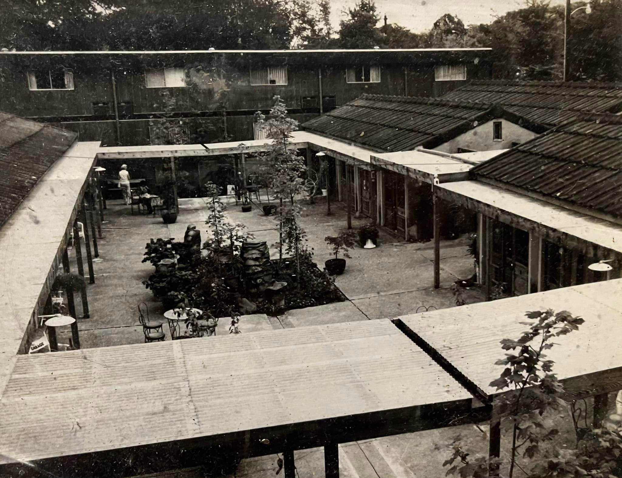 Black and white photo looking down over the courtyard, showing the original layout of buildings and pergolas