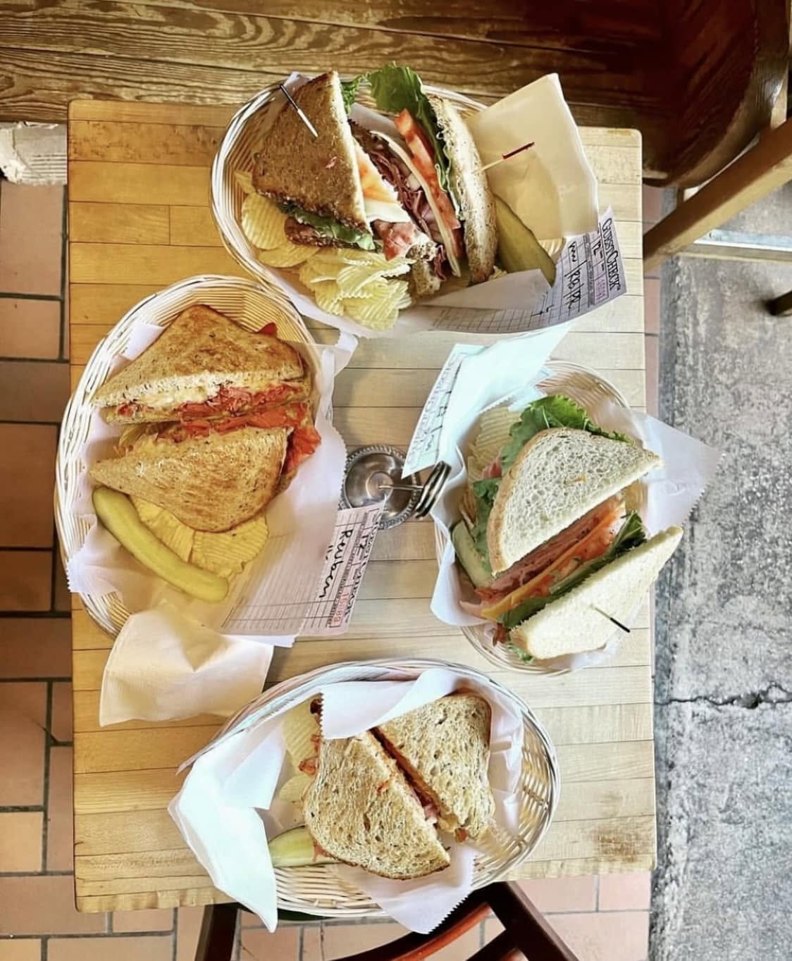 Close-up of a basket full of our infamous club sandwiches with chips and pickles