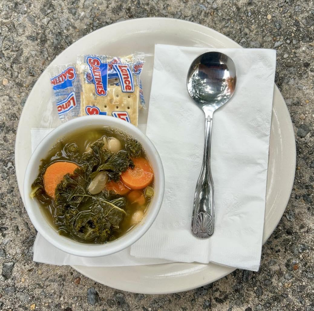 A bowl of vegetable soup with saltine crackers